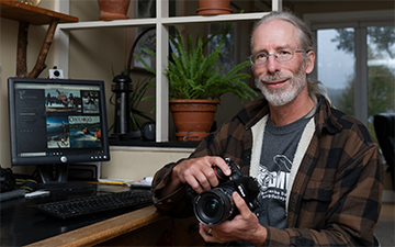 James Smedley in his home office with camera in hand.